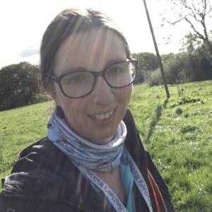 Happy dog walker smiles at camera. Lanyard reads Heather's Walkies